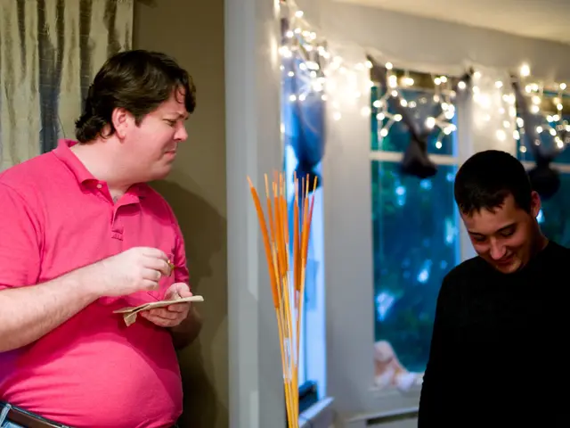 In the image there are two men, the second person is holding some paper in his hand and in the...